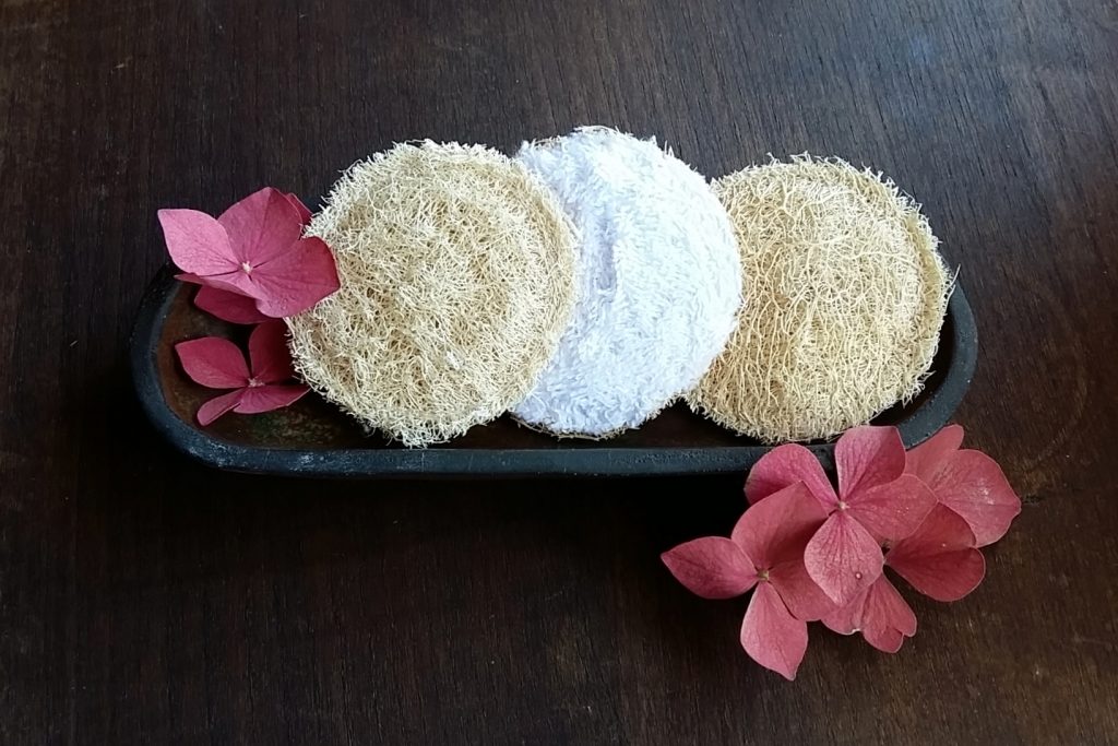 Esponjas naturales con flores decorativas sobre bandeja.