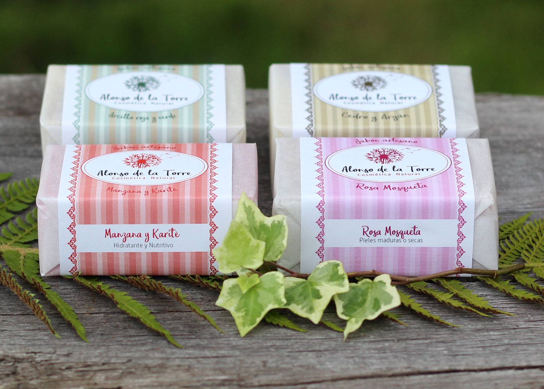 Jabones artesanales sobre madera y hojas decorativas.